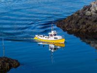 Kleiner Fischkutter spiegelt sich im ruhigen Wasser des Hafens Arnarstapi